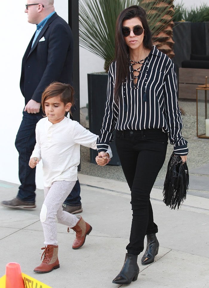 Mason Dash Disick looks casual in a white top, gray pants, and tan lace-up boots