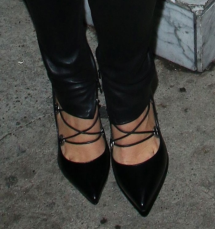 A closer look at Kourtney Kardashian's Saint Laurent "Paris" pumps, featuring pointed toes, corset-inspired lacing, and silver-tone D-ring hardware that adds an edgy twist to the classic black stiletto
