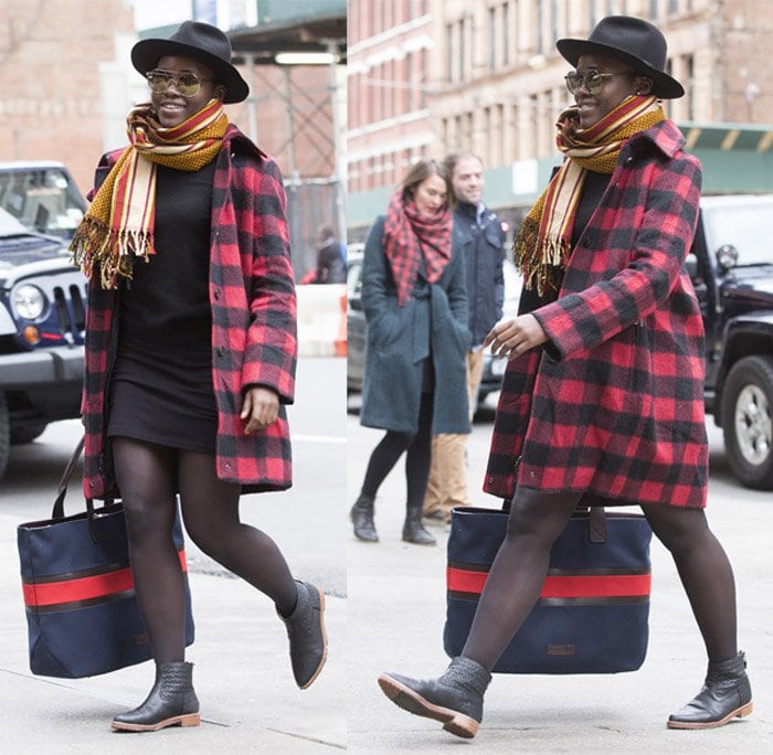 Lupita Nyong’o elevates her street style in a red-and-black Woolrich wool-blend plaid coat, sheer tights, and ankle booties, pairing cozy textures with chic Parisian flair