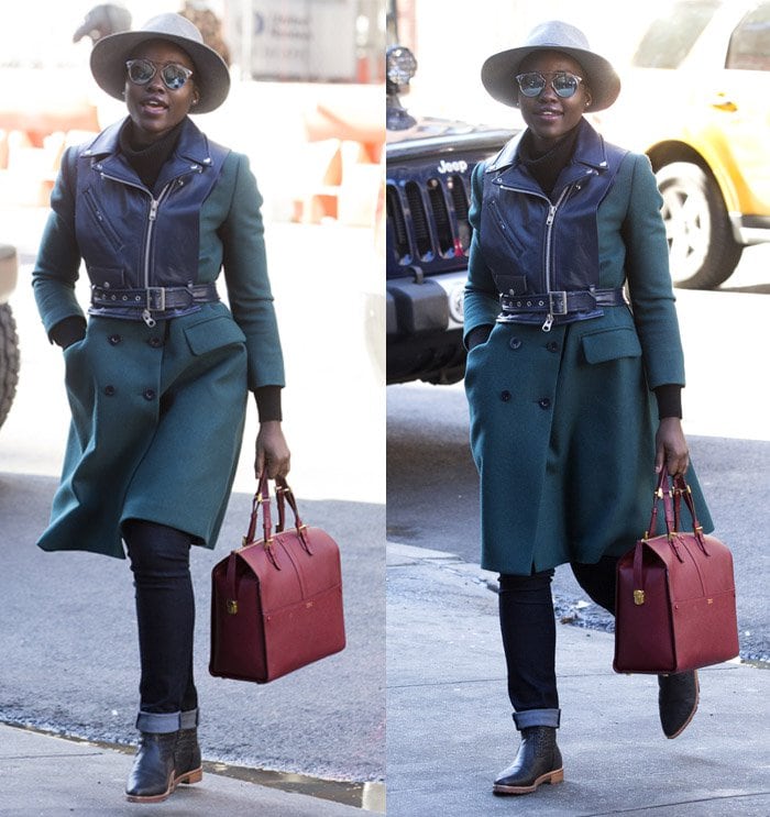 Lupita Nyong’o adds a bold pop of color to her chic winter look, pairing a green double-breasted coat and belted leather jacket with a striking red Giorgio Armani Borgonuovo bag and ankle booties