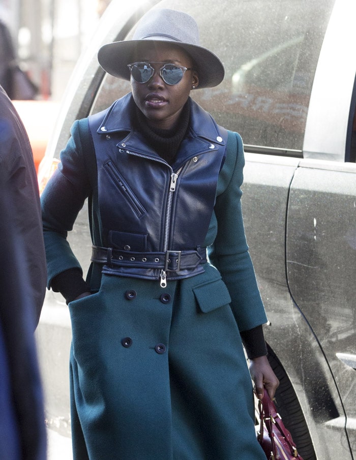 Lupita Nyong’o arrives in New York for the Eclipsed matinee on November 21, 2015, layering a green double-breasted coat over a belted leather jacket for a polished winter statement look