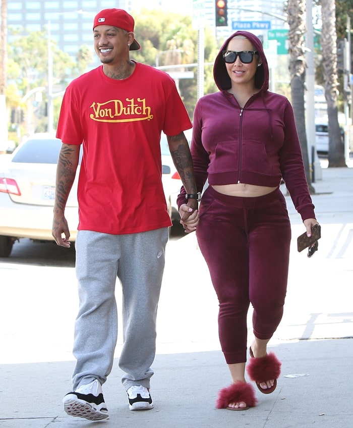 Amber Rose paired a cropped burgundy velvet hoodie and matching joggers with fluffy slide sandals for a casual lunch outing with Alexander Edwards in Los Angeles