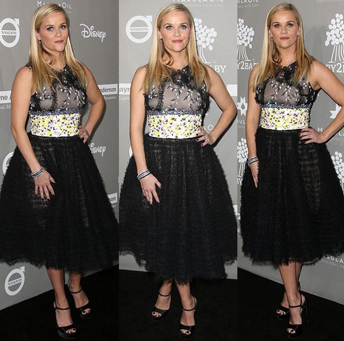 Reese Witherspoon poses confidently on the red carpet, letting the volume of her tulle skirt and the clean lines of her footwear anchor the look