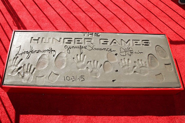 The Hunger Games cast immortalized their handprints, footprints, and signatures in cement at TCL Chinese Theatre