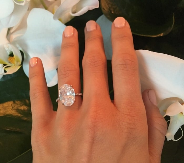 Julianne Hough's exquisite oval diamond engagement ring shines brilliantly, set against a backdrop of delicate white orchids