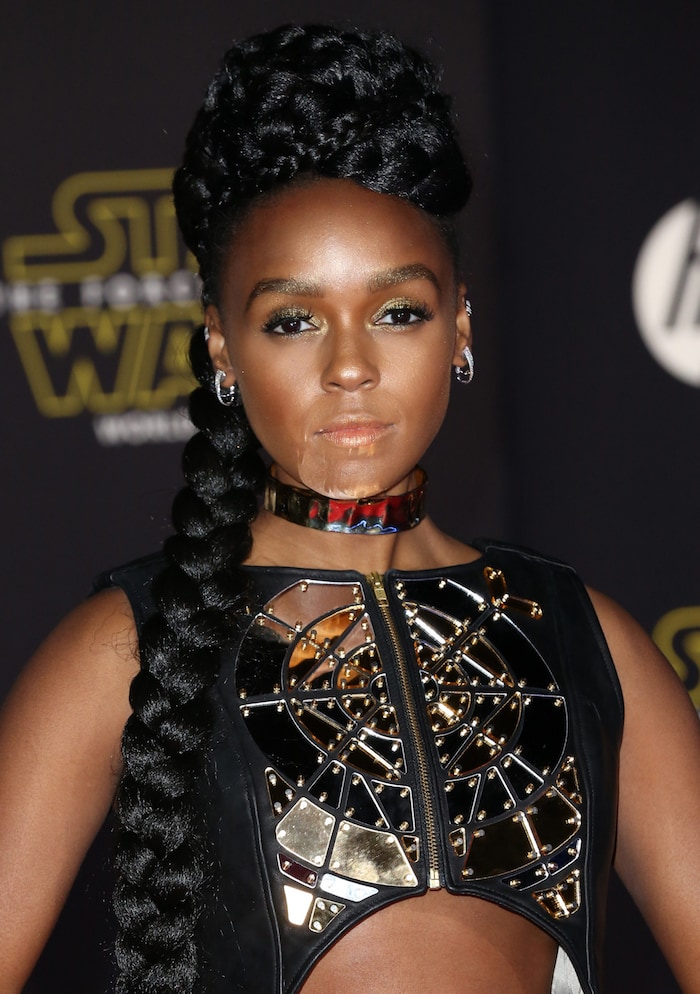 Janelle Monáe captivates with her intricate mirrored top, bold metallic choker, and flawless braided updo, exuding futuristic elegance on the red carpet at the premiere of "Star Wars: The Force Awakens"