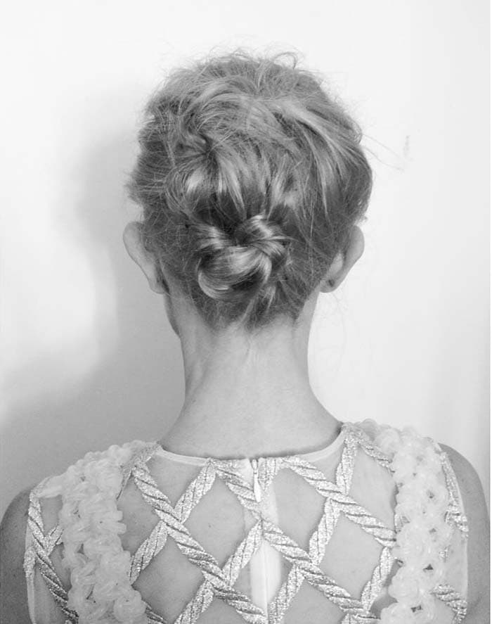 Her neatly twisted updo exposes the sheer back and silver embroidery of the Simone Rocha dress while keeping its intricate texture unobstructed