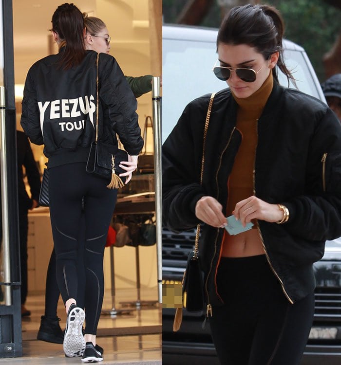 Kendall Jenner sports a black bomber jacket with "Yeezus Tour" printed on the back, paired with a toffee-colored cropped turtleneck and black leggings, completing her sporty-chic look with Nike Flyknit sneakers