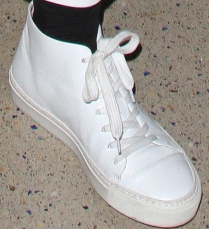 A closer look at Kylie Jenner’s minimalist white Acne Studios sneakers — styled with contrasting black socks for a clean, high-top finish that perfectly complements her monochrome airport outfit