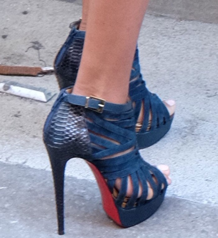 A closer look reveals the python-textured heel counters and bold red soles of La La’s teal Christian Louboutin “Karina” booties