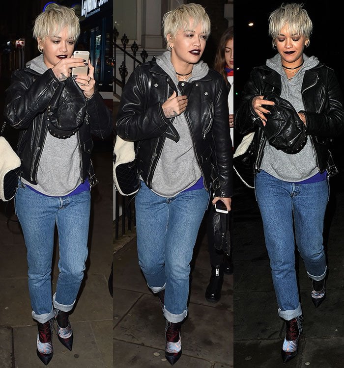 Rita Ora's complete outfit showcases her platinum pixie, layered hoodie under a leather jacket, cuffed jeans, and unique printed ankle boots