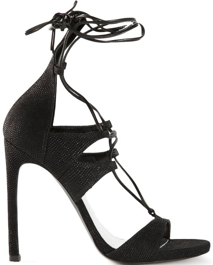 Stuart Weitzman’s black LegWrap sandals combine a sleek peep-toe silhouette with intricate lace-up straps that wind dramatically around the ankle, creating one of the brand’s most recognizable red-carpet designs
