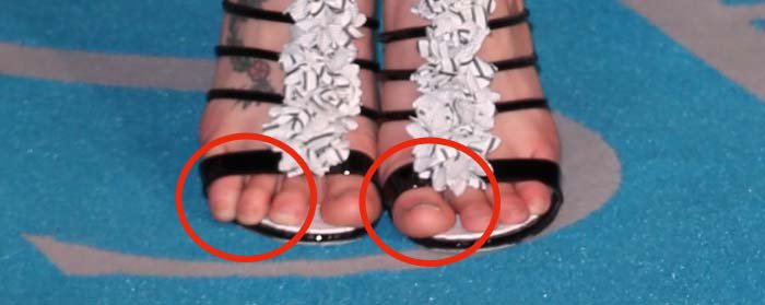 Kaya Scodelario’s right-foot floral vine tattoo subtly steals the spotlight, framed by glossy black straps and a clean, understated pedicure