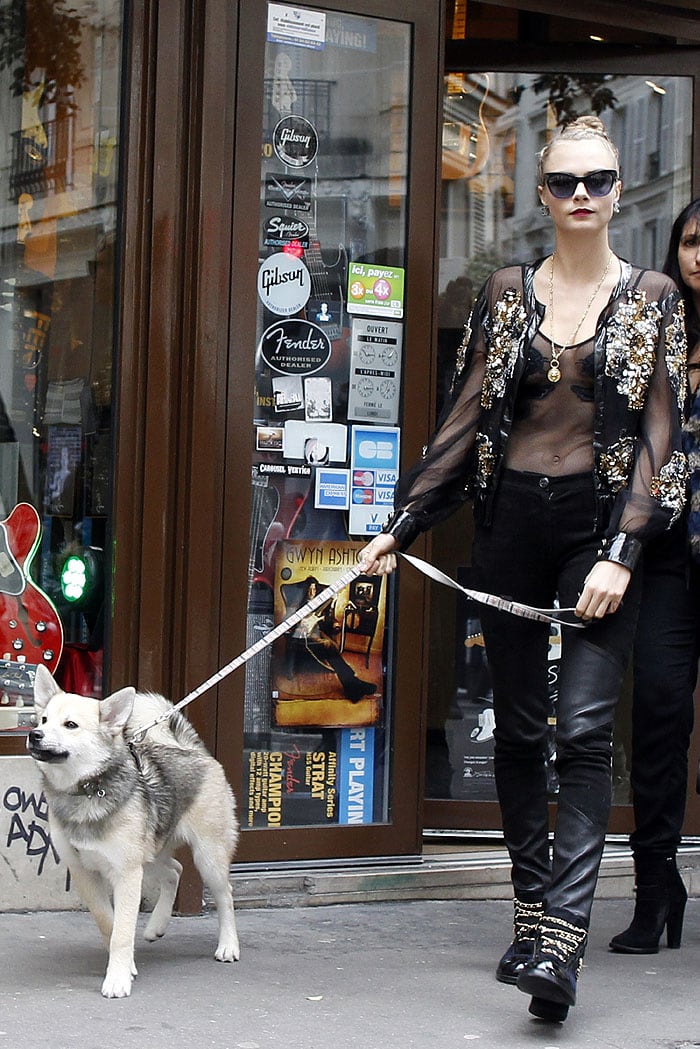 Cara Delevingne and her dog Leo stroll in front of the Guitar Legend store in Paris
