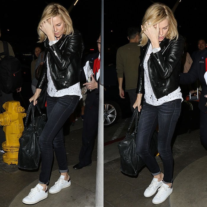 Charlize Theron sharpens a classic T-shirt-and-jeans airport uniform with clean white sneakers, letting the streamlined footwear balance her leather jacket and off-duty essentials at Los Angeles International Airport (LAX) on March 13, 2015