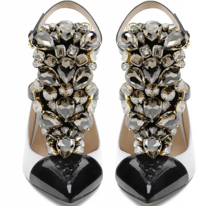 Gedebe “Mimi” pumps in white leather feature glossy black cap toes, slender ankle straps, and a dramatic cascade of faceted crystal embellishments