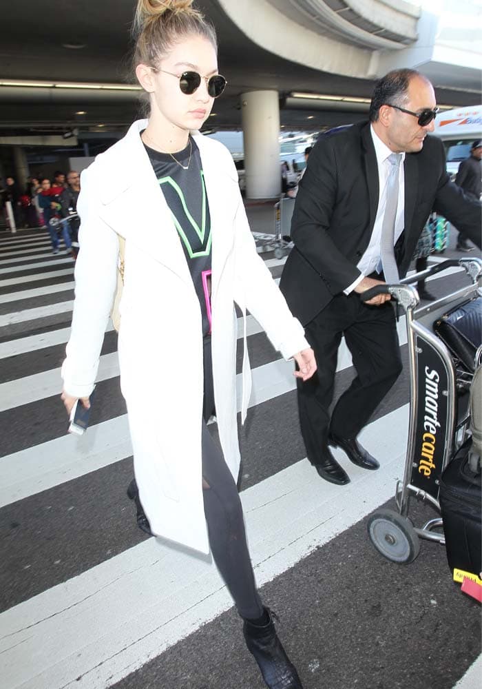 Gigi Hadid wears a Versace sweatshirt and Beyond Yoga pants as she arrives at LAX