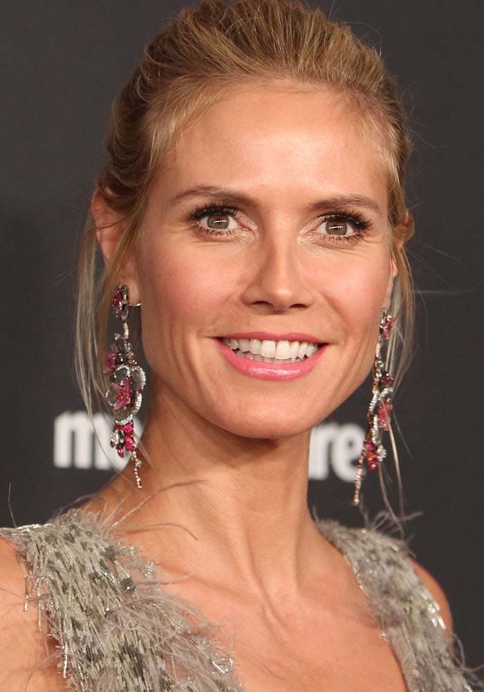 Heidi Klum keeps her glam refined with swept-back hair and cascading gemstone earrings that echo the shimmer of her fringe gown