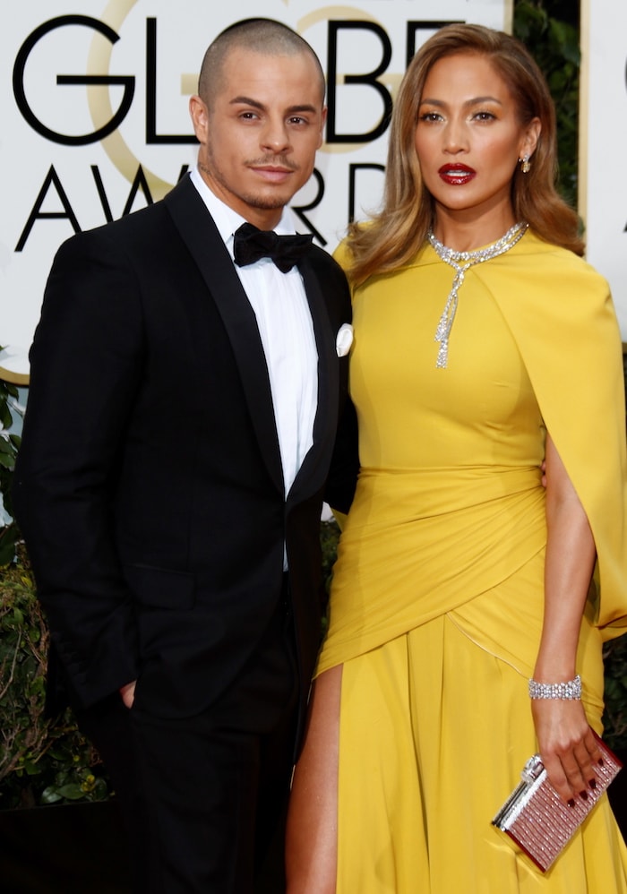 Jennifer Lopez and Casper Smart pose together on the Golden Globes red carpet, with the gown’s sculpted cape-style shoulder bringing structure to her yellow couture look