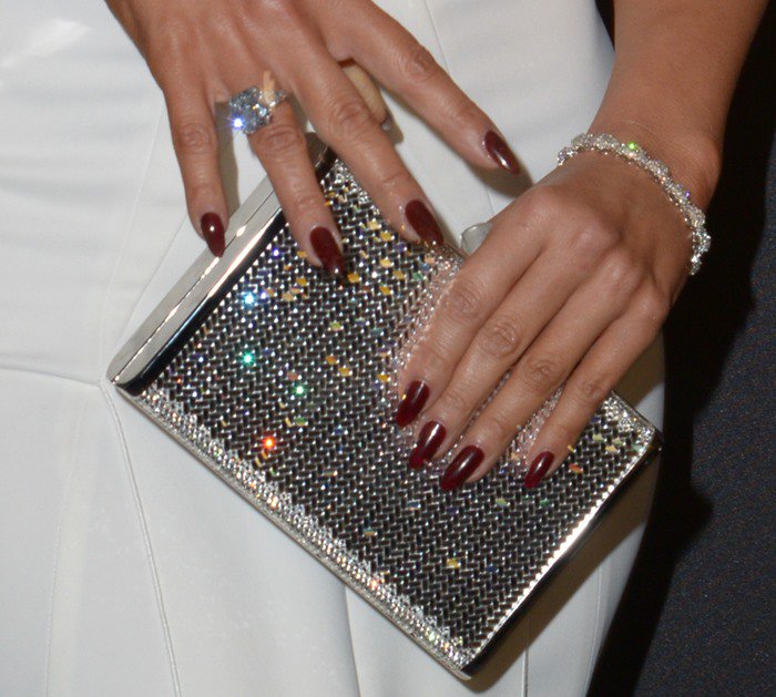 Jennifer Lopez carries a crystal Judith Leiber clutch with diamond jewelry and dark red nails