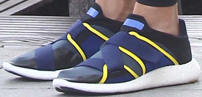 Jessica Alba’s feet in blue-and-yellow Adidas x Stella McCartney “Glove” sneakers, featuring elastic cross-straps and a sleek slip-on design set on lightweight white midsoles