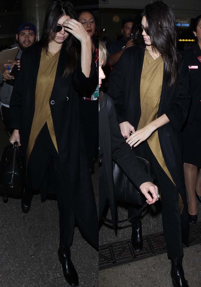 Kendall Jenner keeps it sleek in a brown wrap top, tailored black pants, and a long black coat as she navigates the LAX terminal carrying her Givenchy “Lucrezia” bag and wearing Sandro “Amele” ankle boots