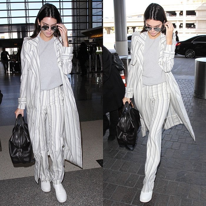 Kendall Jenner sharpens her airport tailoring with clean white shoes, using them to ground a striped suit and long duster