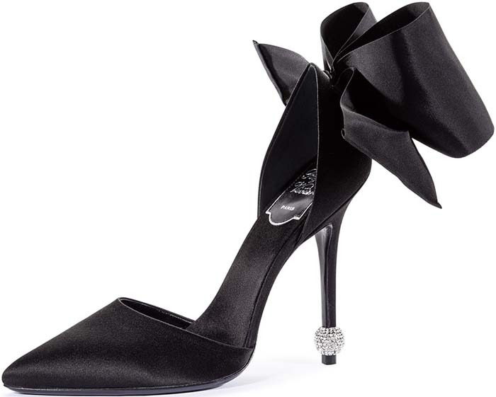 The black satin version highlights the architectural heel bow and slender stiletto, emphasizing the design’s couture craftsmanship and dramatic rear profile