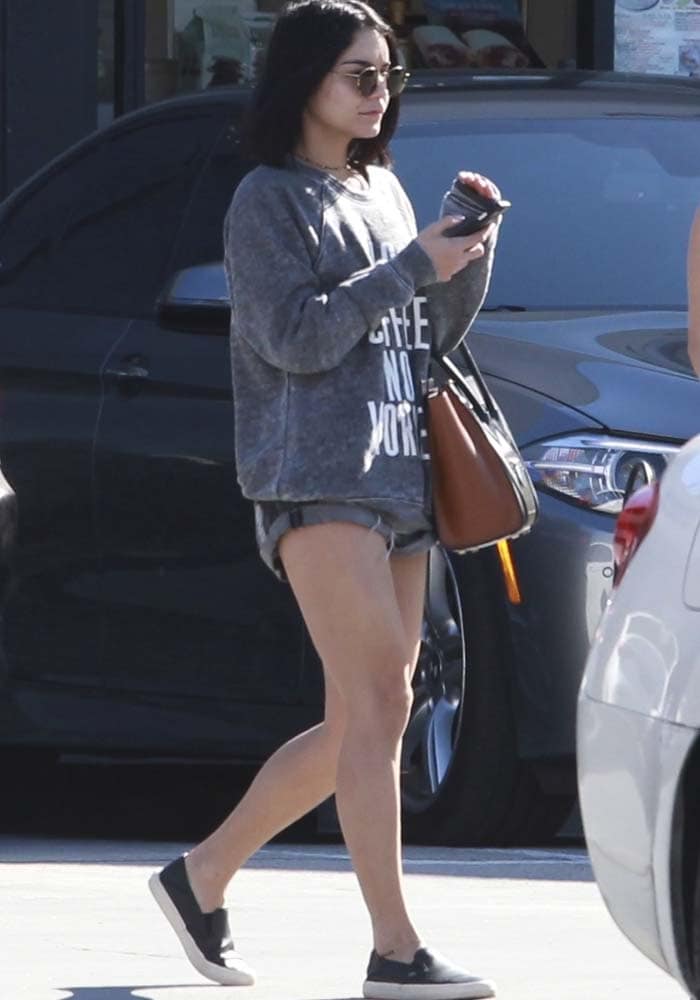 Vanessa Hudgens keeps it casual in a cozy graphic sweater, denim shorts, and slip-on sneakers