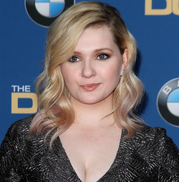 Abigail Breslin paired softly waved blonde hair and bronze-toned makeup with a shimmering Christian Siriano gown, balancing Old Hollywood glamour with youthful elegance