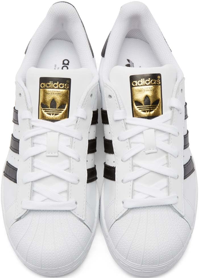 Adidas Originals “Superstar” shell-toe leather sneakers in white with black Three Stripes, the iconic design that has evolved from a 1970s basketball essential into one of the most enduring street-style staples in fashion history