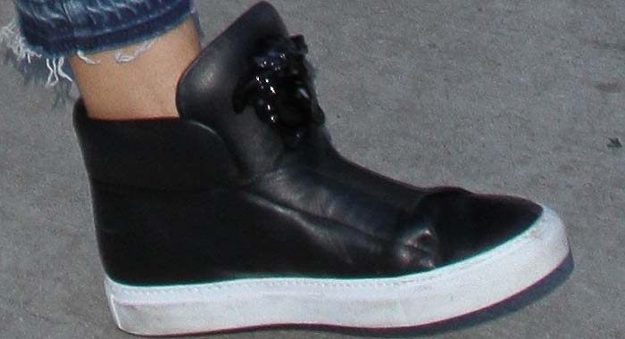 Heidi Klum wears black Versace Medusa high-top sneakers featuring a glossy tonal Medusa emblem, smooth leather construction, and a chunky white rubber sole for bold street style