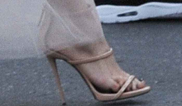 Jennifer Lopez showcased the leg-lengthening appeal of Giuseppe Zanotti's nude patent "Coline" sandals, a minimalist strappy design that blended seamlessly into her monochromatic Valentino ensemble