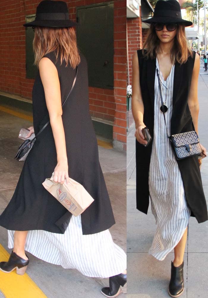 Jessica Alba steps out in Los Angeles wearing a striped maxi dress layered with a sleeveless black vest, a Maison Michel hat, and Midas “Armo” ankle boots