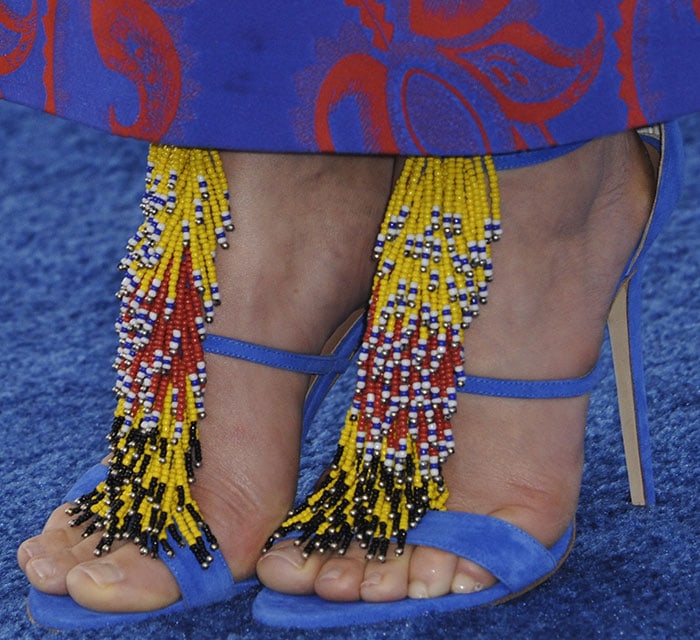 A detailed close-up of the Brian Atwood “Iliana” sandals reveals intricate beaded fringe cascading over vivid blue suede straps