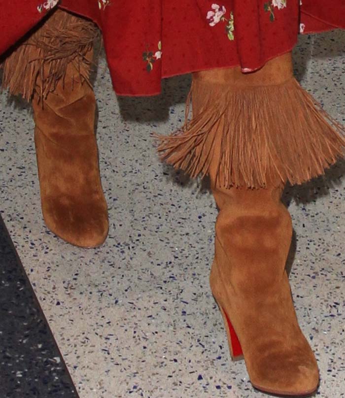 Kate Hudson’s tan suede Christian Louboutin “Majung” boots bring dramatic fringe movement and the label’s signature red soles to her laid-back travel outfit