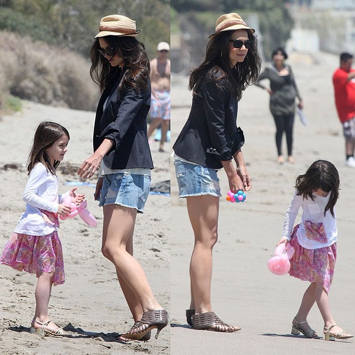 Katie Holmes and daughter Suri Cruise make a fashionable but impractical choice, playing on the beach in heeled sandals and dressy casual outfits