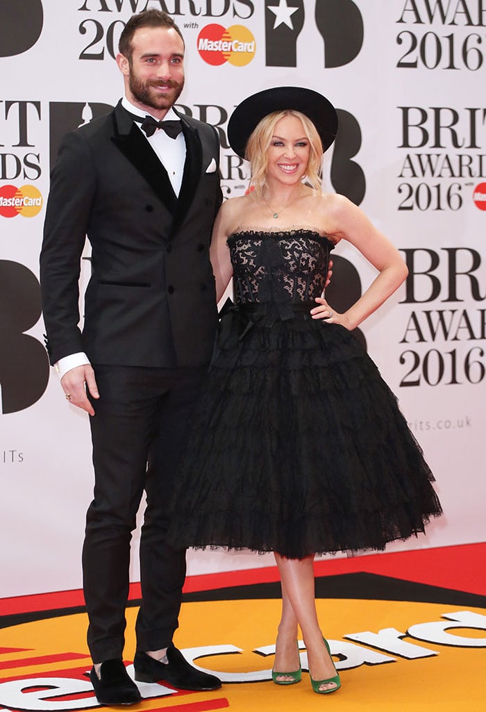 Kylie Minogue and her fiancé Joshua Sasse make a stylish pair on the red carpet at the 2016 BRIT Awards, with Kylie in a dramatic black lace dress by Dolce Gabbana and Joshua in a classic black tuxedo