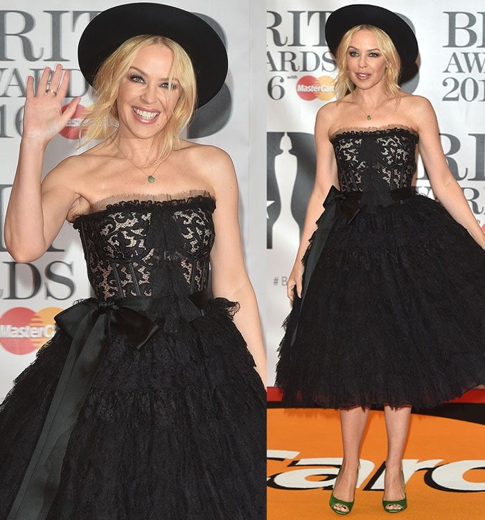 Kylie Minogue channels vintage glamour in a strapless black lace Dolce Gabbana dress, complete with a cinched waist bow and a voluminous tiered skirt, adding a modern twist with a playful wide-brimmed hat