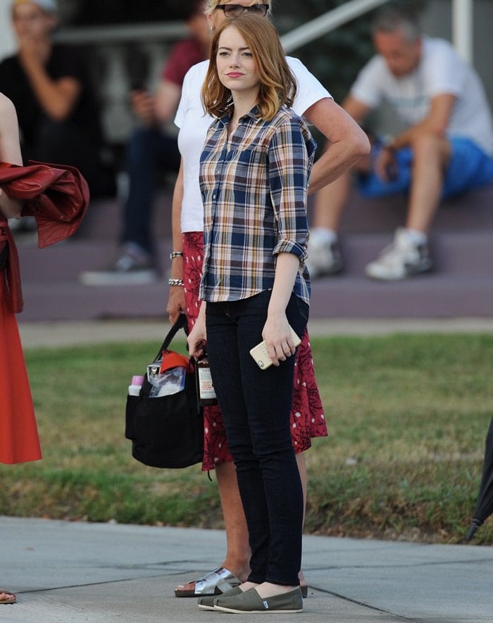 Emma Stone keeps it casual in olive green TOMS slip-ons, skinny jeans, and a plaid shirt while filming 'La La Land' in Pasadena on August 18, 2015