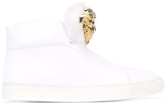 Versace Medusa high-top sneakers in crisp white leather are elevated by a gold-tone Medusa head plaque, with a clean, minimal upper and matching white rubber sole that emphasizes the design’s sculptural simplicity