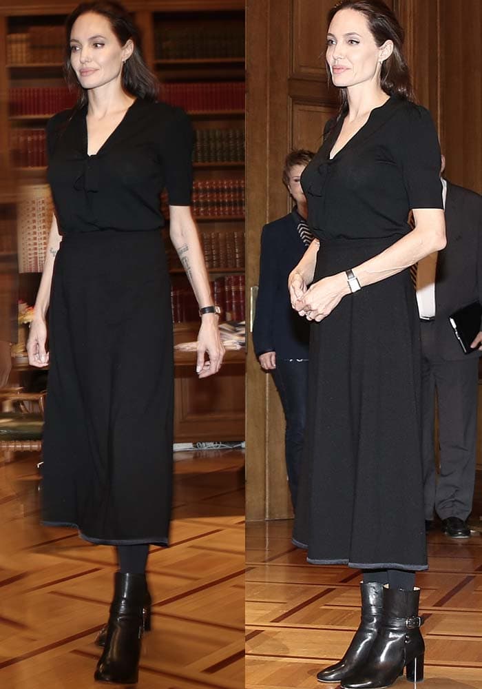 Angelina Jolie keeps her diplomatic wardrobe understated in a black bow-front blouse, midi skirt, opaque tights, and Isabel Marant “Raley” ankle boots