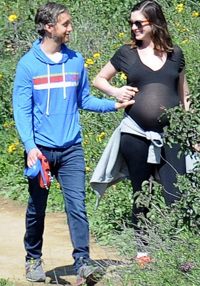 Anne Hathaway enjoys a sunlit hike with husband Adam Shulman, pairing a black tee and leggings with her Asics Gel-Kinsei trainers, while a gray jacket tied at the waist keeps the look practical and relaxed