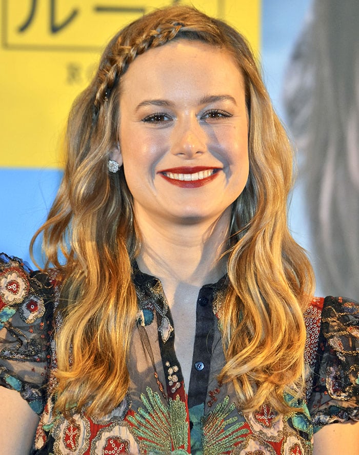 Brie Larson lit up the Tokyo press conference with loose, golden waves accented by a chic braided headband and a bold red lip