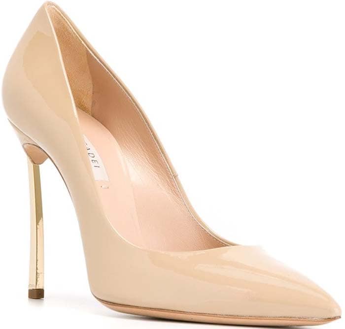 The Casadei “Blade” pump in nude patent leather features the brand’s signature razor-thin metallic stiletto heel for a sharply sculpted finish
