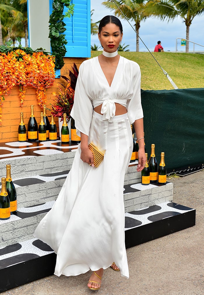 Chanel Iman exudes effortless elegance in a flowing white Jonathan Simkhai two-piece outfit paired with gold Stuart Weitzman sandals at the Veuve Clicquot Carnival