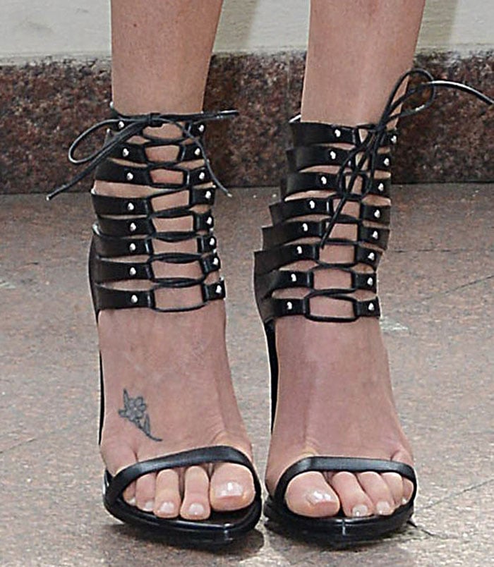 Charlize Theron makes a bold statement in Alexandre Vauthier lace-up stiletto sandals, letting the cage-like straps and her signature foot tattoo take center stage