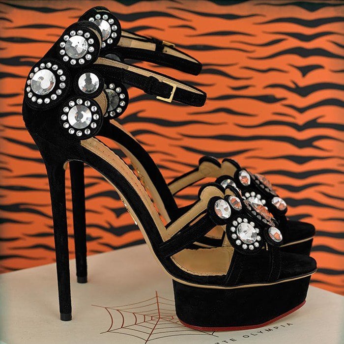 The Charlotte Olympia “Precious” sandals featured clustered circular crystals across the toe and ankle panels, contrasting with their sleek black suede construction