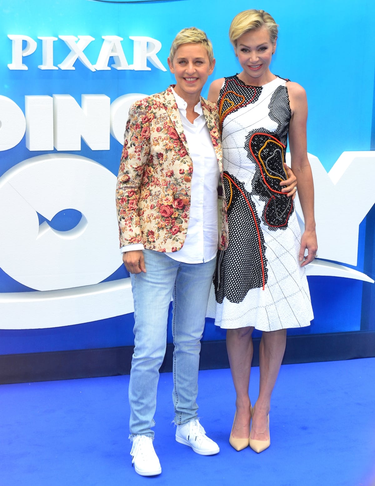 Ellen DeGeneres keeps her signature casual style in a floral blazer, white shirt, slim jeans, and crisp white sneakers, while Portia de Rossi elevates the blue-carpet moment in a Bottega Veneta Spring 2016 abstract appliqué dress paired with nude Sergio Rossi pointed-toe pumps