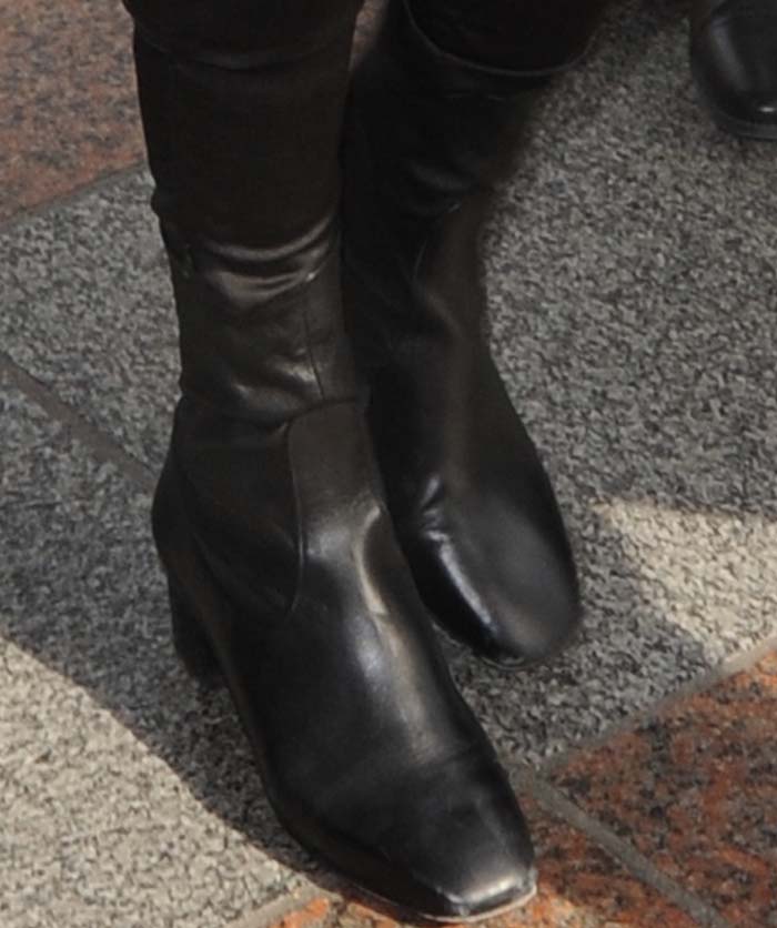 A closer look at Gigi Hadid’s sleek black Sandro Paris “Amele” ankle boots featuring a soft sock-style upper and block heel — a minimalist favorite also worn by Kendall Jenner